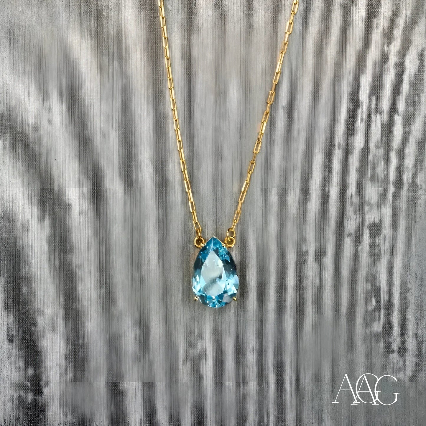 Gold necklace featuring a teardrop-shaped blue topaz pendant and 18 carat gold chain