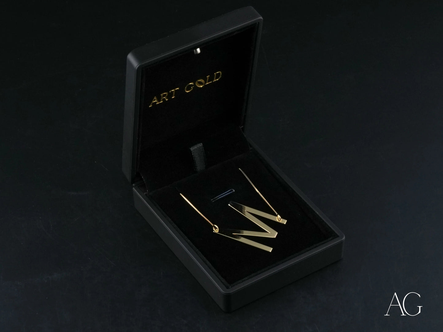 Gold earrings in a black jewelry box with personalized initial letter pendant necklace