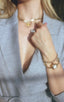 woman in gray blazer wearing gold bracelet and gold bracelet
