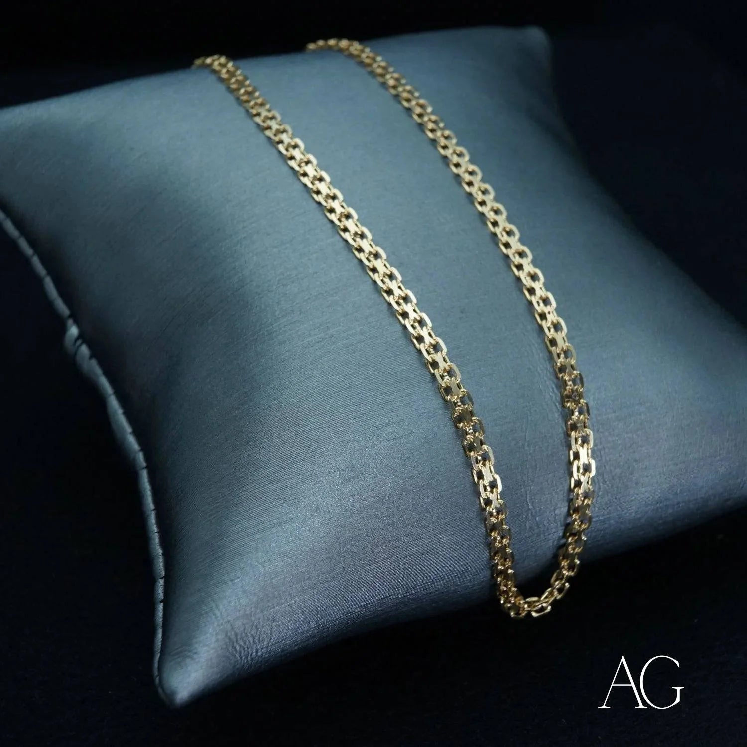 Gold chain necklace on dark cushion showcasing authentic 18k gold modern jewelry design