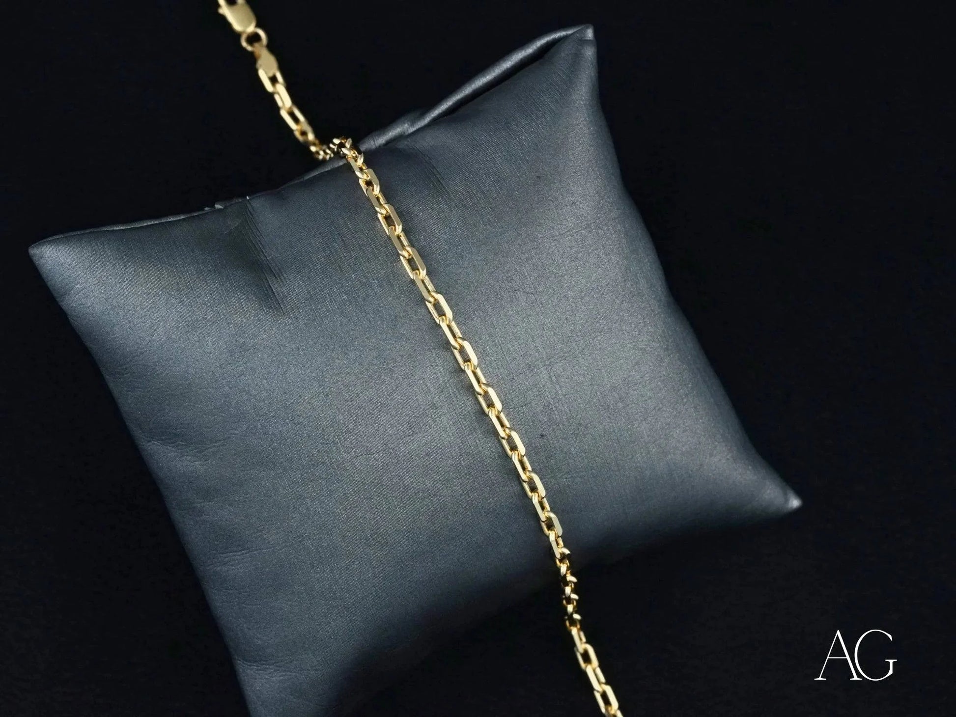 18k solid gold bracelet with diamond-cut link design on a gray cushion