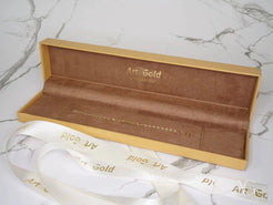 Rectangular gold jewelry box with velvet interior featuring 18k gold kid’s ID bracelet with flower motif and spring ring lock