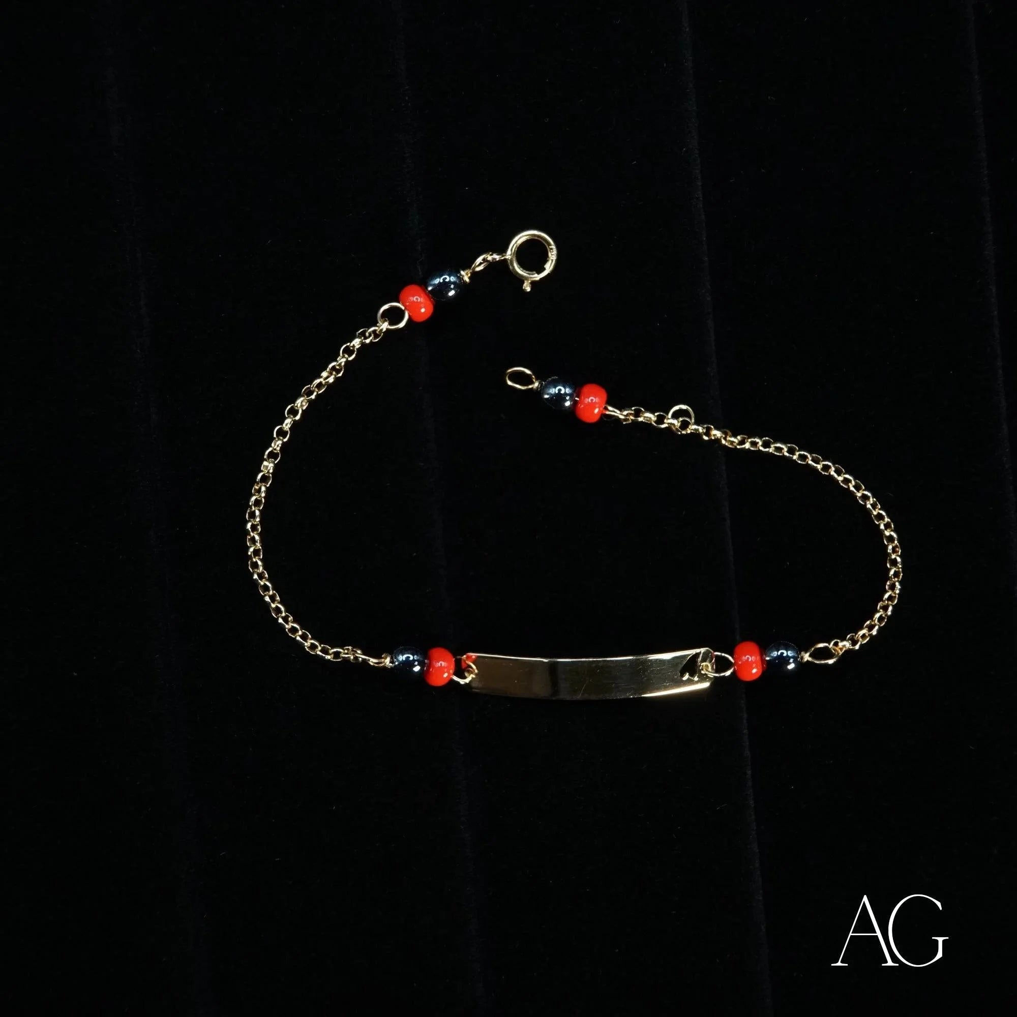 Delicate silver bracelet showcasing small red beads and heart symbol in 18k gold design