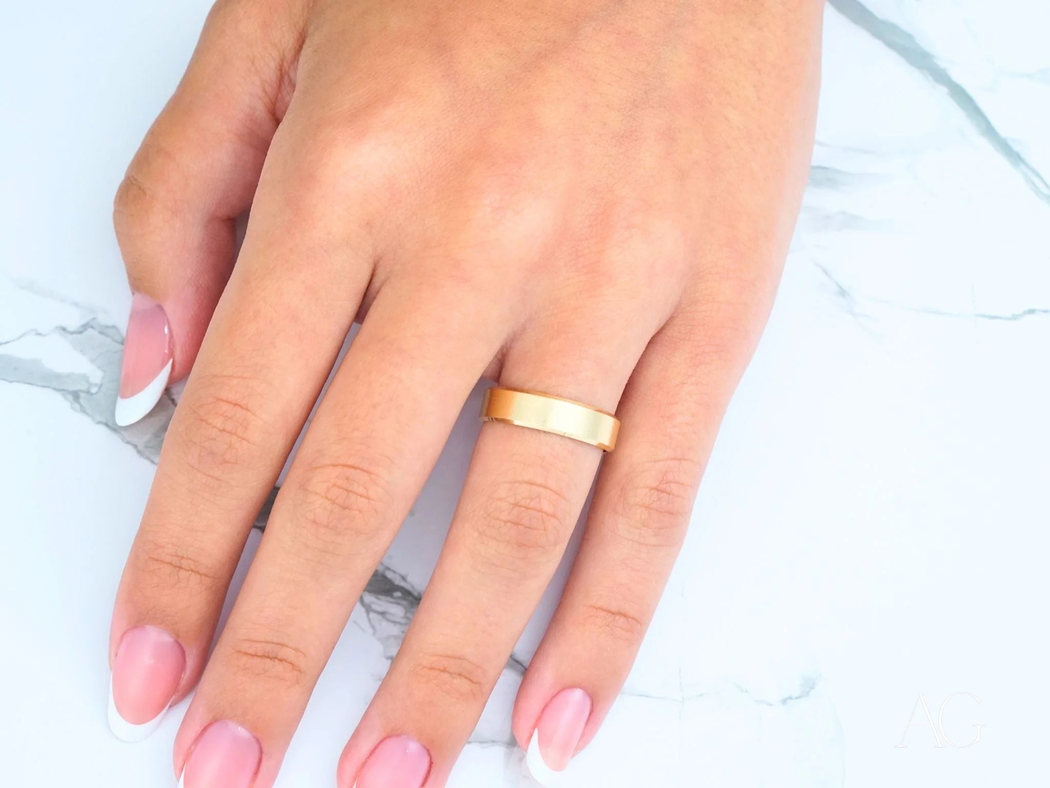 Gold wedding band on ring finger with pink nails showcasing Modern Elegance design