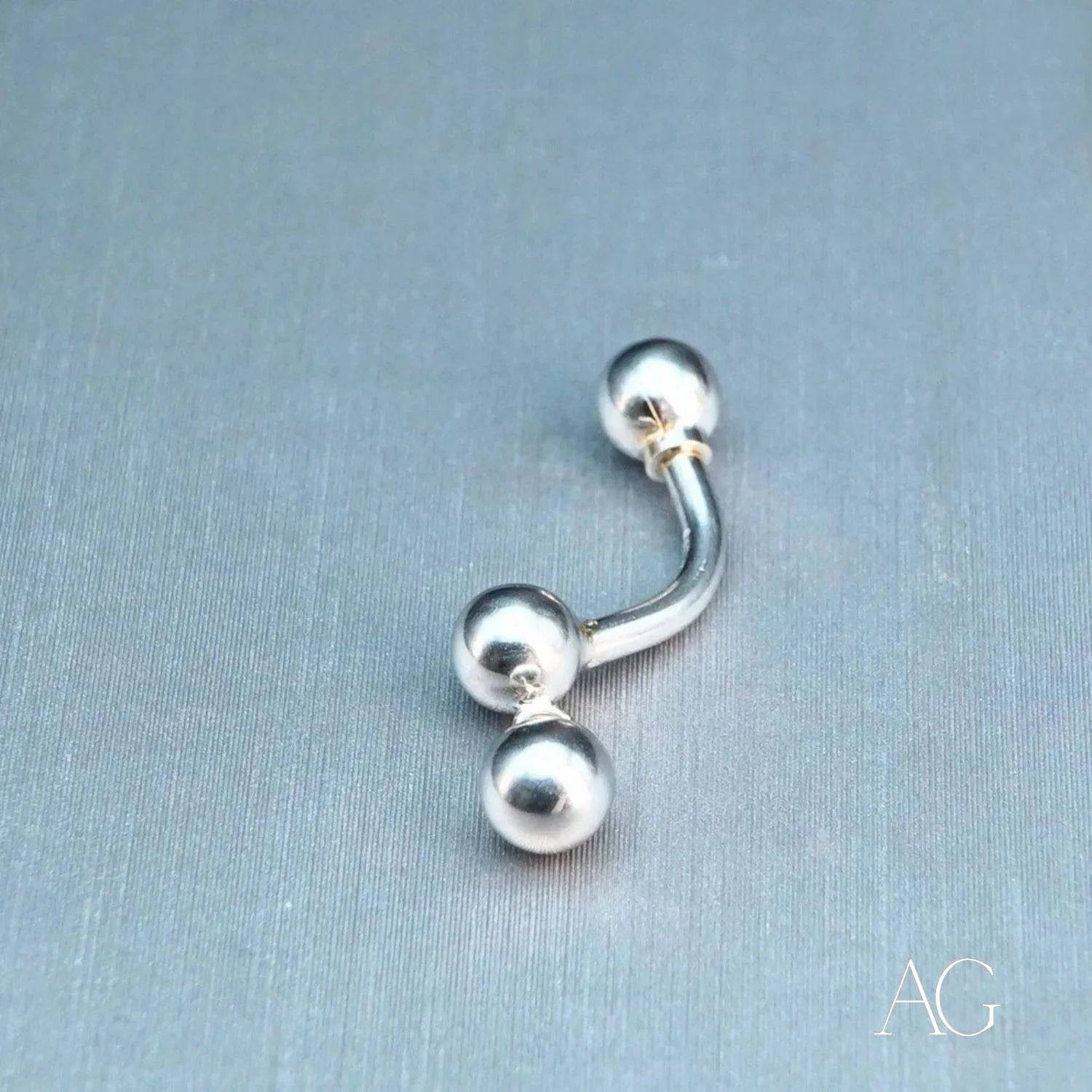 Silver curved barbell piercing with three spherical ends in 18k white gold design