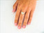 Heart-shaped diamond ring on a finger with pink nails in 18k yellow gold elegance
