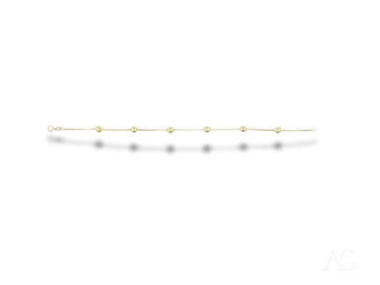 Delicate 18k gold bracelet featuring polished gold spheres and small green gemstones