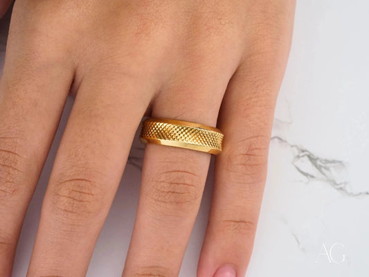 Gold textured 18k gold wedding band ring with classic fit worn on a finger
