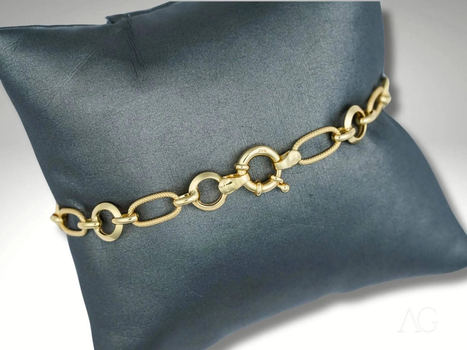 Elegant 18k gold bracelet with unique links showcased on dark cushion, art gold jewelry