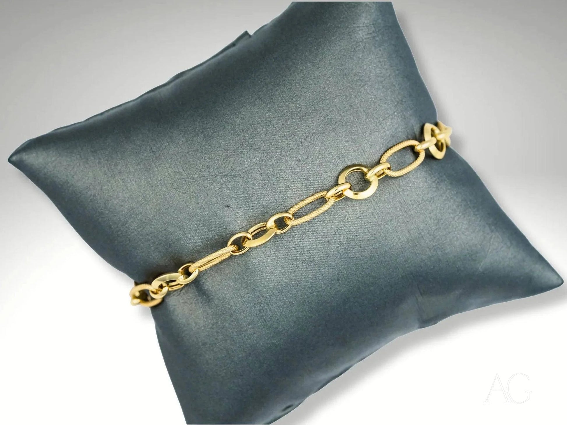 Elegant 18k gold bracelet on dark gray cushion showcasing art gold jewelry craftsmanship