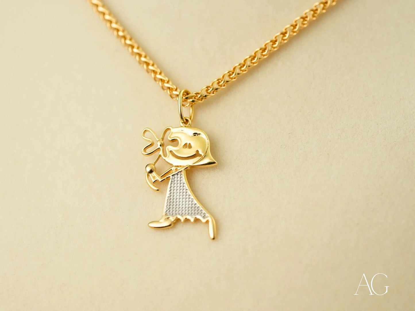 Gold Doll Pendant featuring a stick figure charm in 18k gold with textured dress pattern
