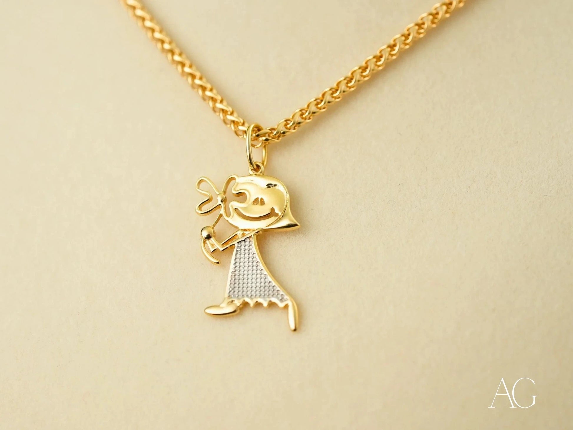 Gold Doll Pendant featuring a stick figure charm in 18k gold with textured dress pattern