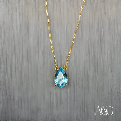 Gold necklace featuring a teardrop-shaped blue topaz pendant and 18 carat gold chain