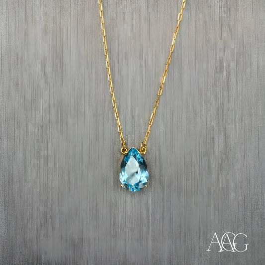 Gold necklace featuring a teardrop-shaped blue topaz pendant and 18 carat gold chain