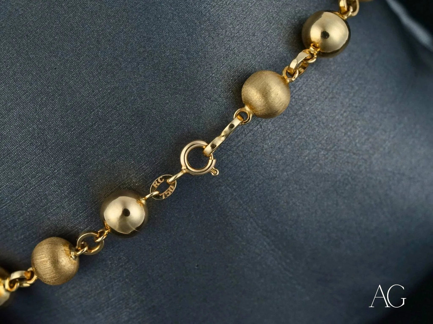 Gold bead bracelet featuring smooth and textured spheres with a spring ring clasp