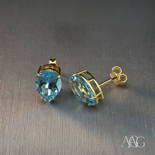 Pair of gold earrings featuring teardrop-shaped blue topaz gemstones in a sleek design