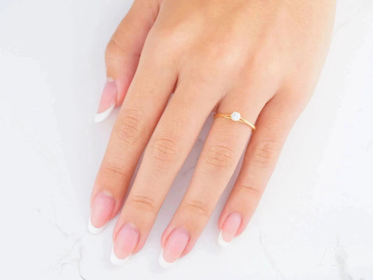 Delicate 18k yellow gold ring with a small pearl on a woman’s hand for everyday elegance