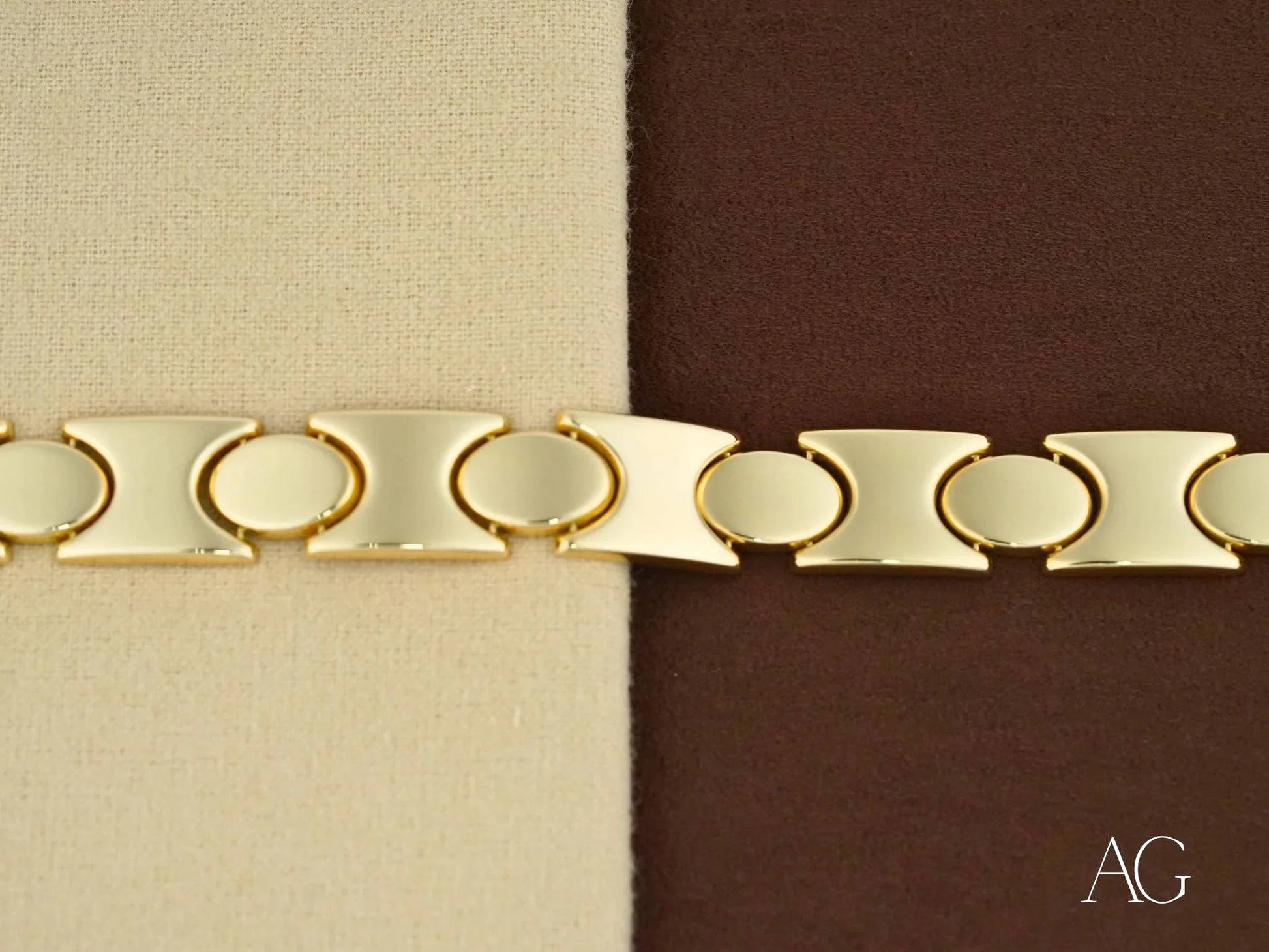 Gold-toned metal bracelet with oval links and flat segments featuring a box clasp design