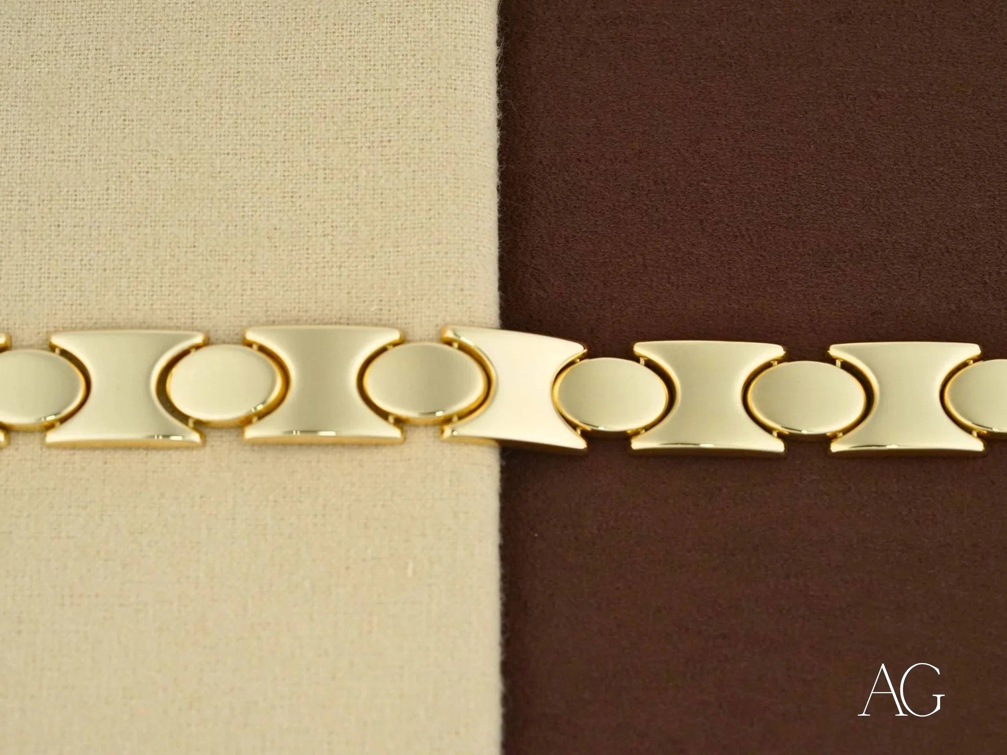 Gold-toned metal bracelet with oval links and flat segments featuring a box clasp design