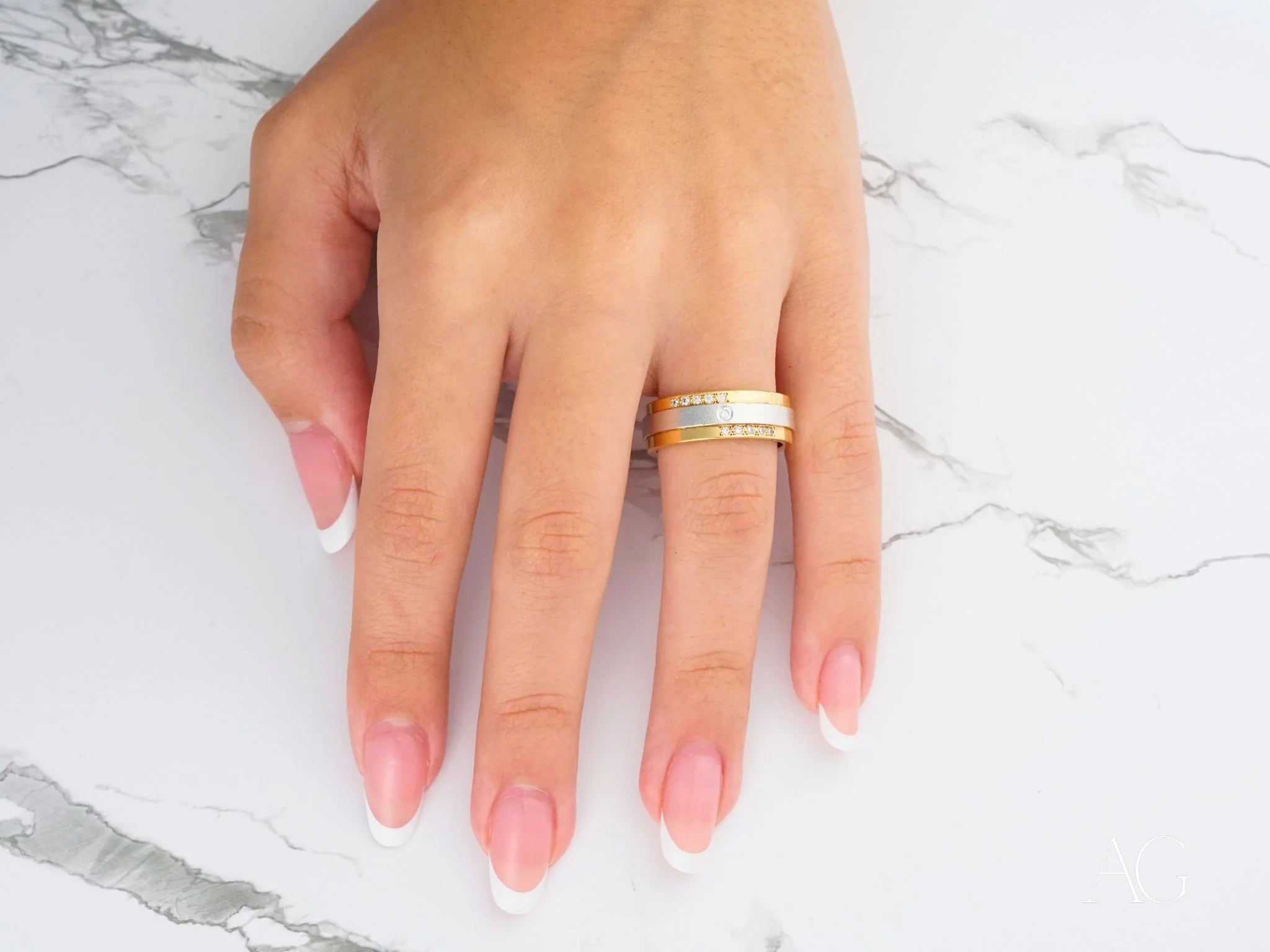 Celestial Grace Two-Tone Gold Wedding Band on a finger with pink manicured nails