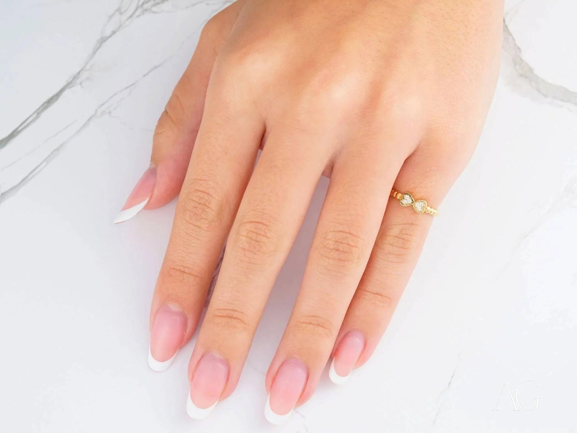 Hand with manicured nails showcasing a Charming 18k yellow gold bow CZ ring