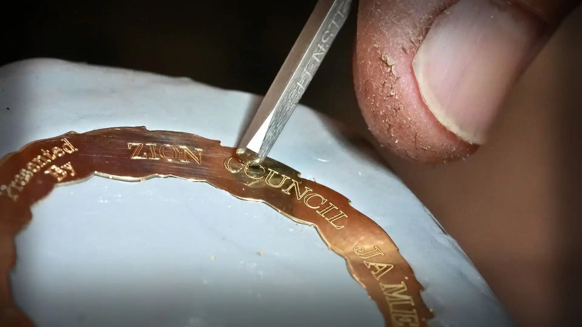 Coin being scratched or marked with a metal tool.