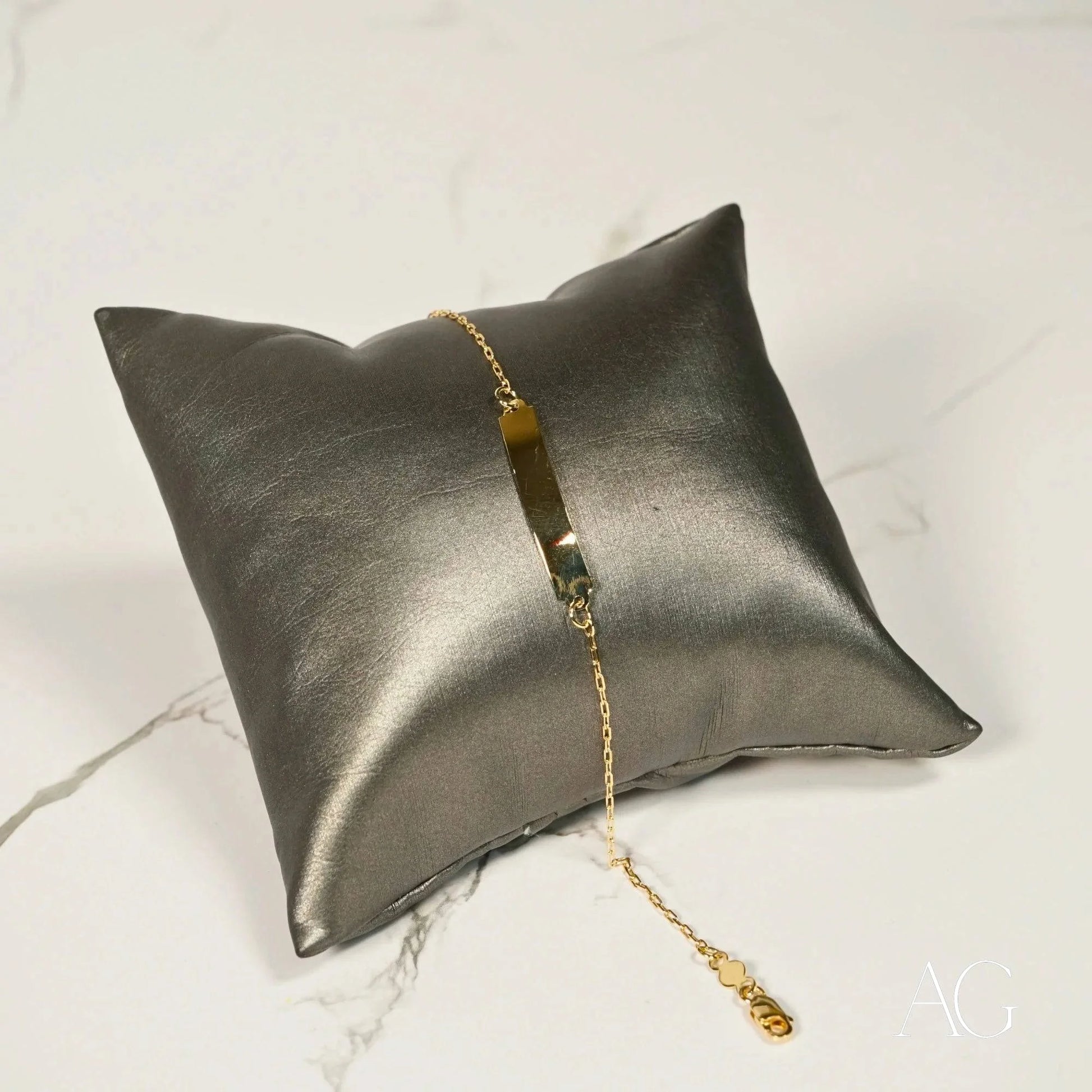 Metallic silver cushion featuring a delicate gold chain bracelet with 18k solid gold