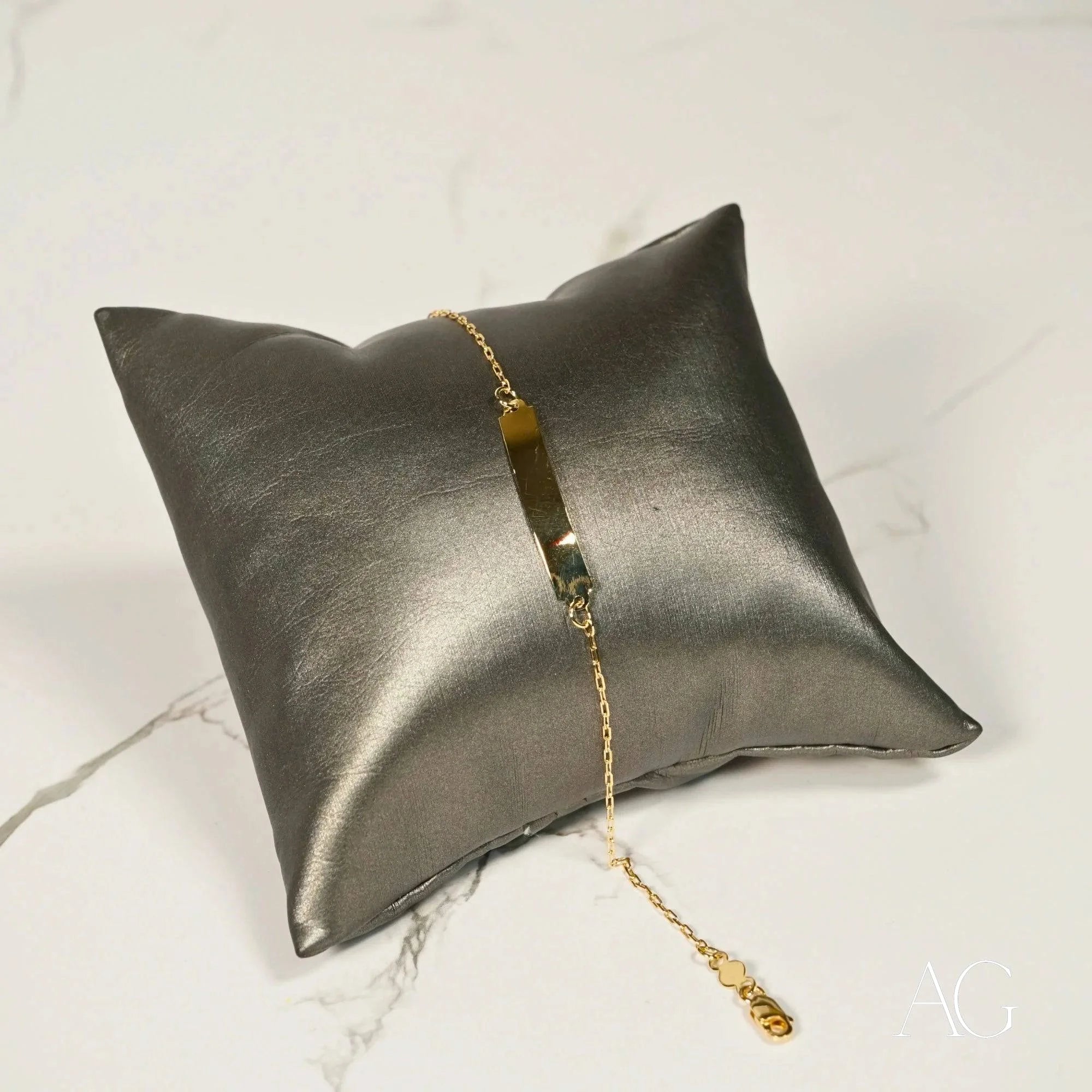 Metallic silver cushion featuring a delicate gold chain bracelet with 18k solid gold