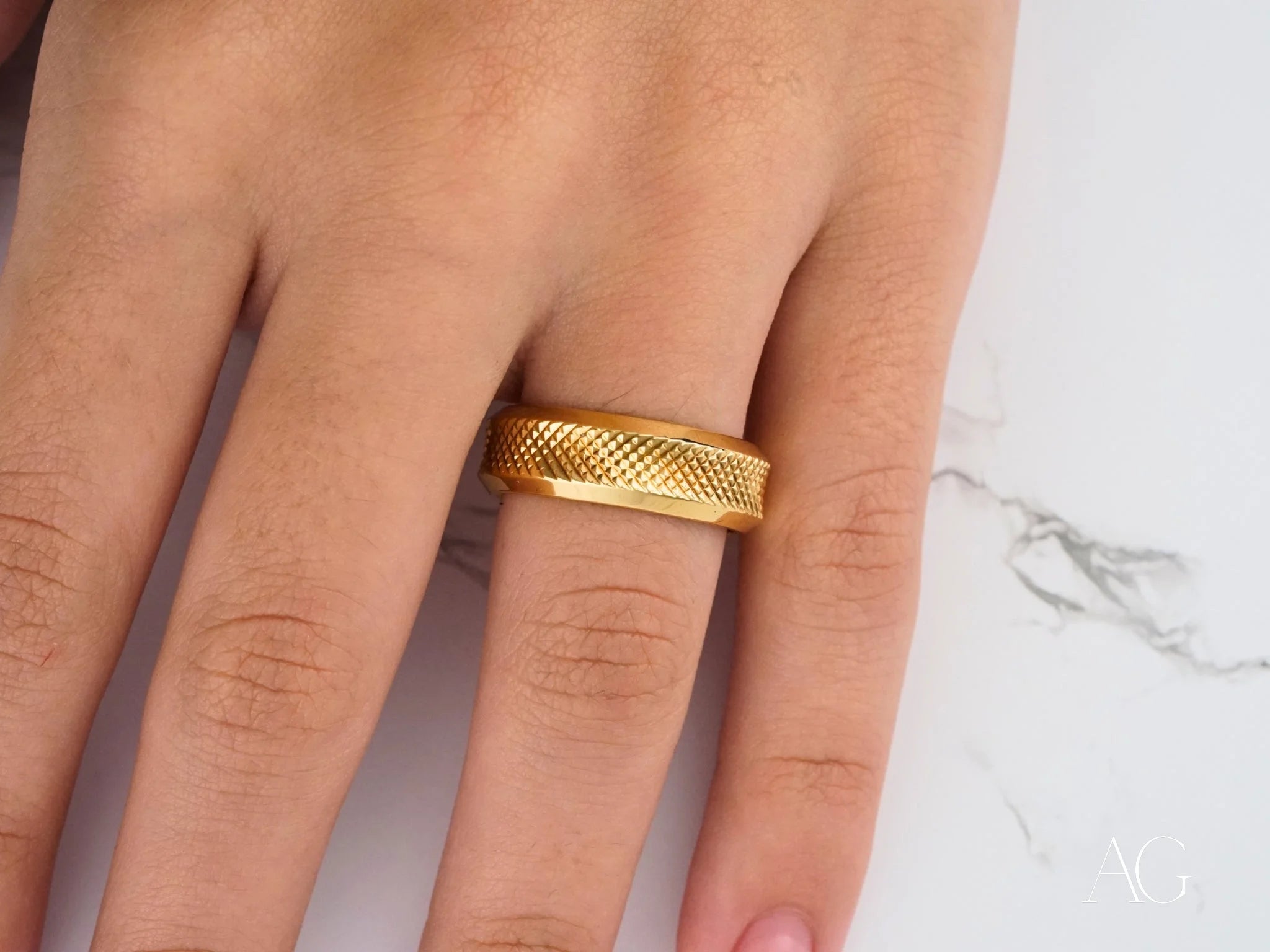 Gold textured 18k gold wedding band ring with classic fit worn on a finger