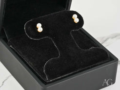 Pearl stud earrings in a black jewelry box, showcasing elegant art gold jewelry design