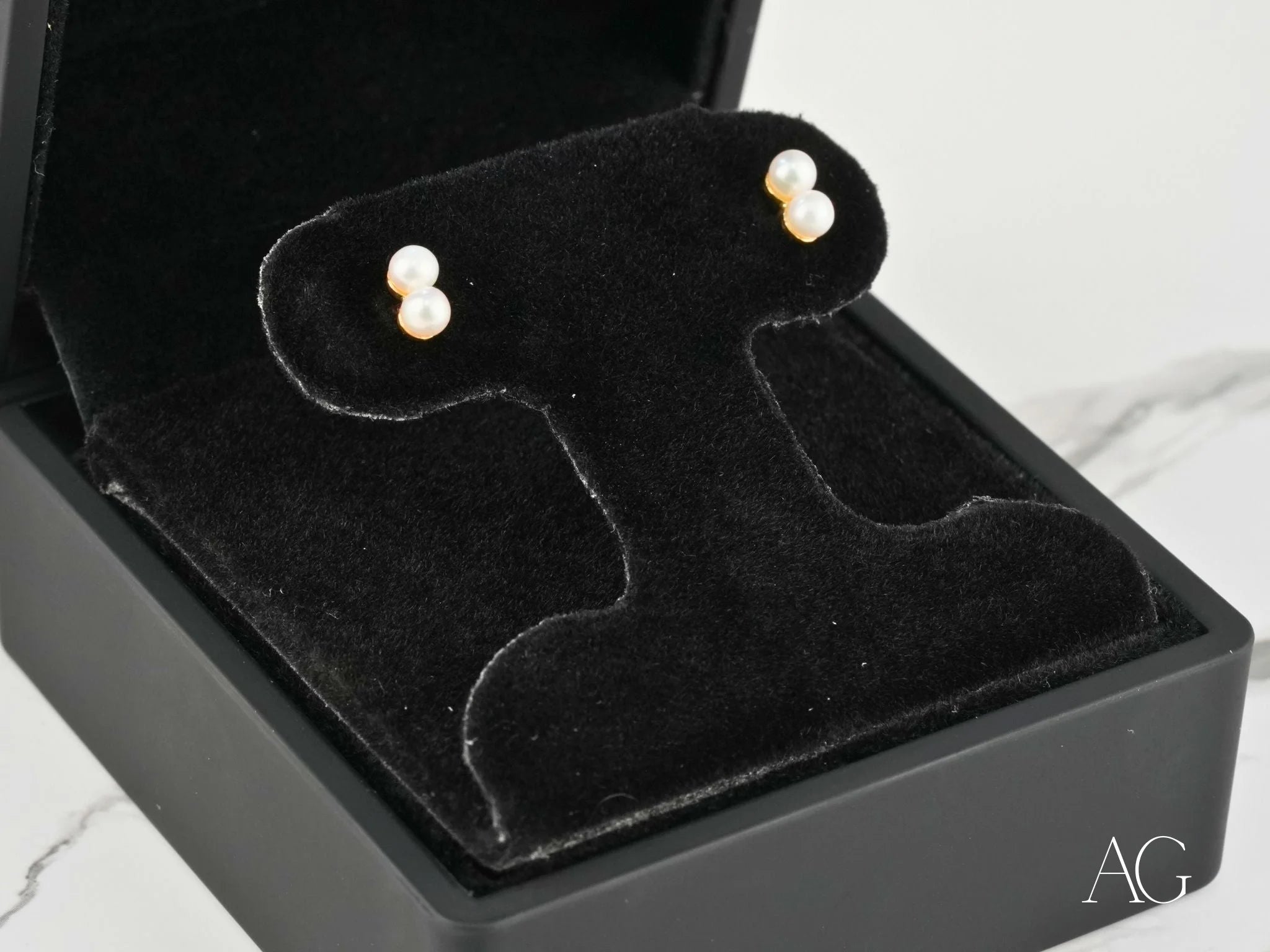 Pearl stud earrings in a black jewelry box, showcasing elegant art gold jewelry design