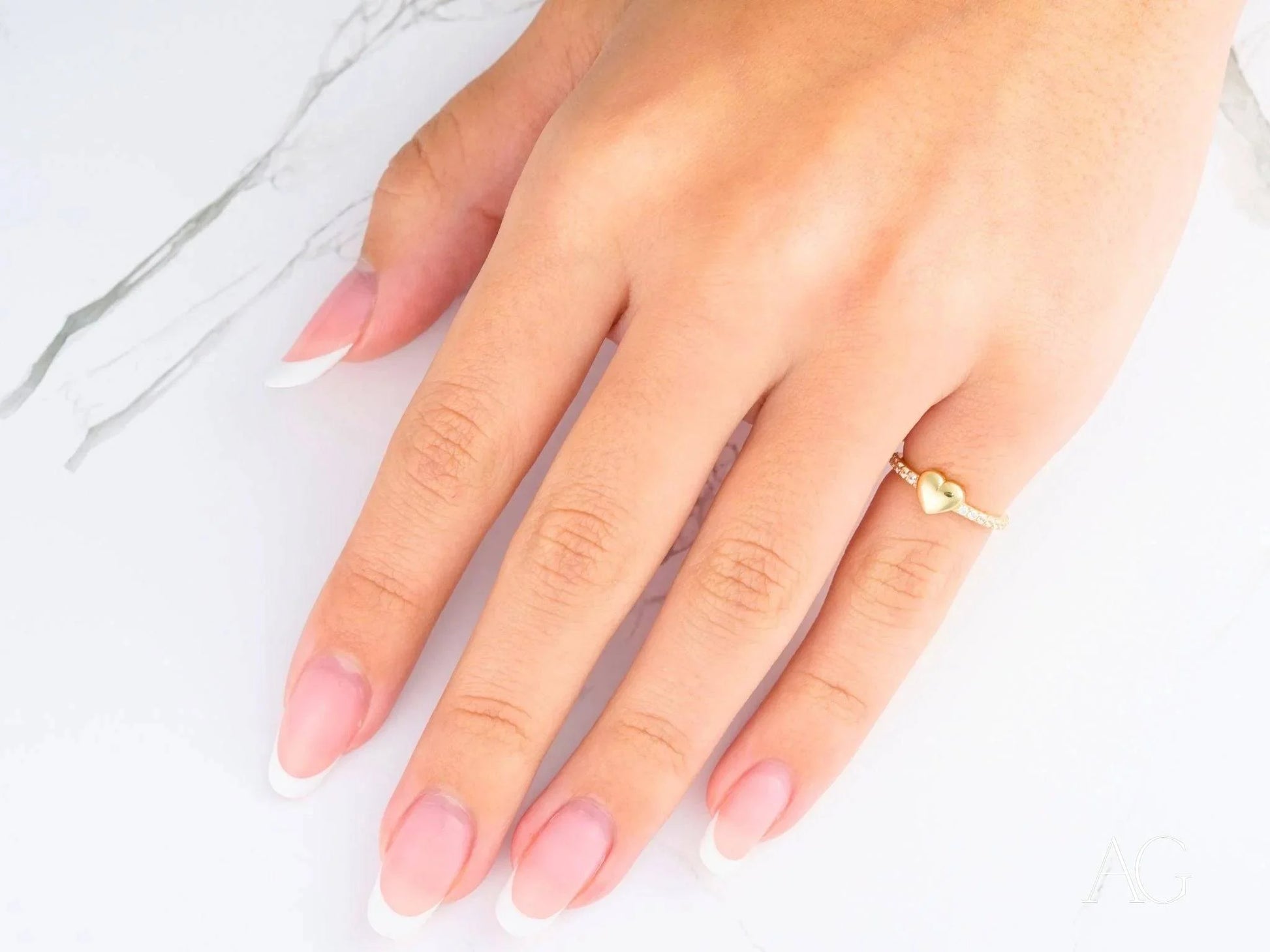 Hand with manicured nails showcasing an 18k yellow gold CZ heart ring