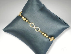 Elegant 18k gold bracelet with infinity symbol and beads on gray cushion