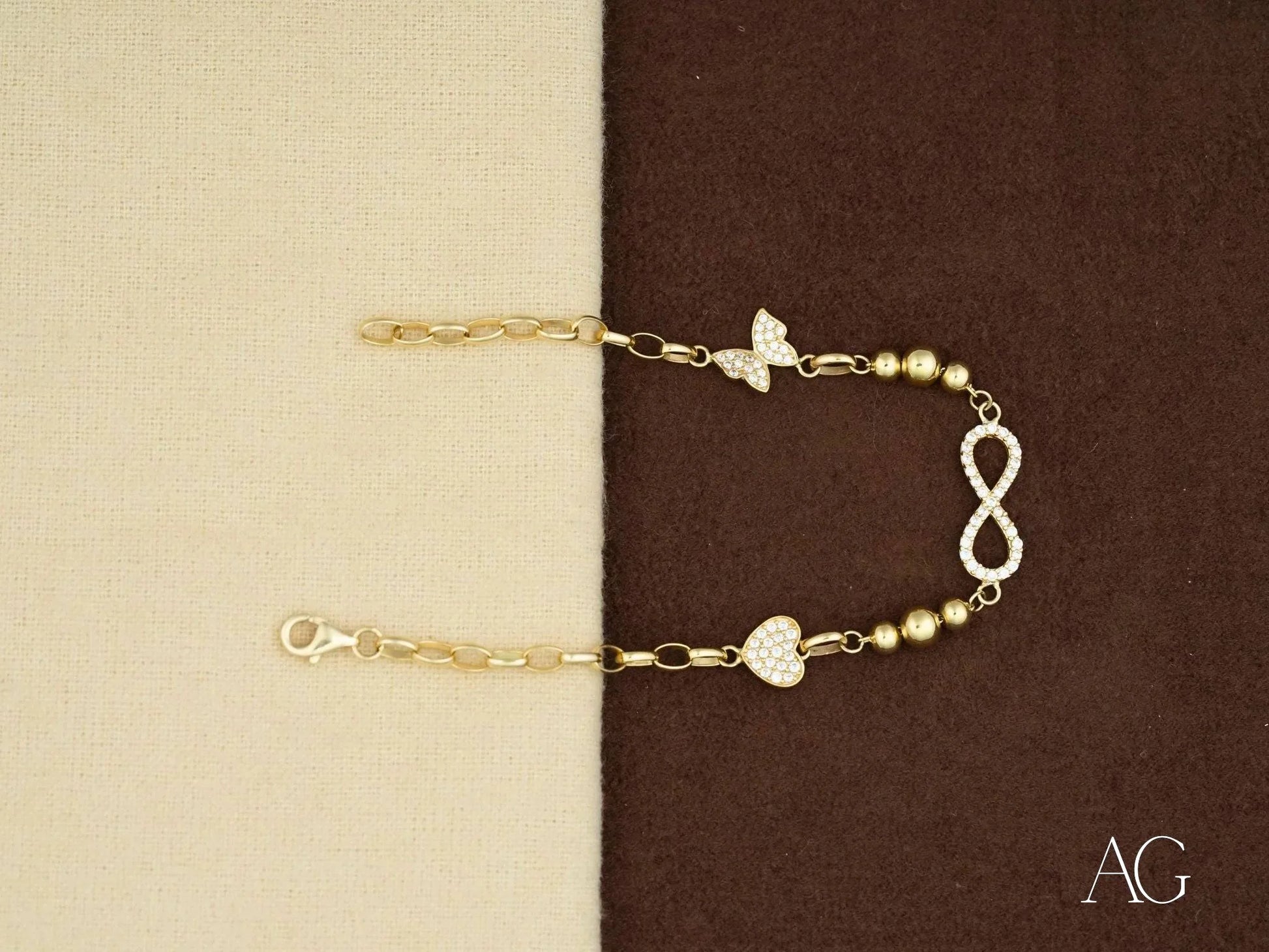 Delicate 18k gold bracelet with infinity symbol and heart charm, adorned with cubic zirconia