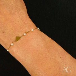 Delicate 18k gold heart bracelet with pearl accents elegantly worn on a wrist