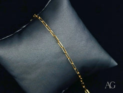 Elegant 18k gold link bracelet on a gray cushion for timeless sophistication