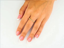 Hand with pink nails wearing an 18k yellow gold square shape ring, showcasing minimalist luxury