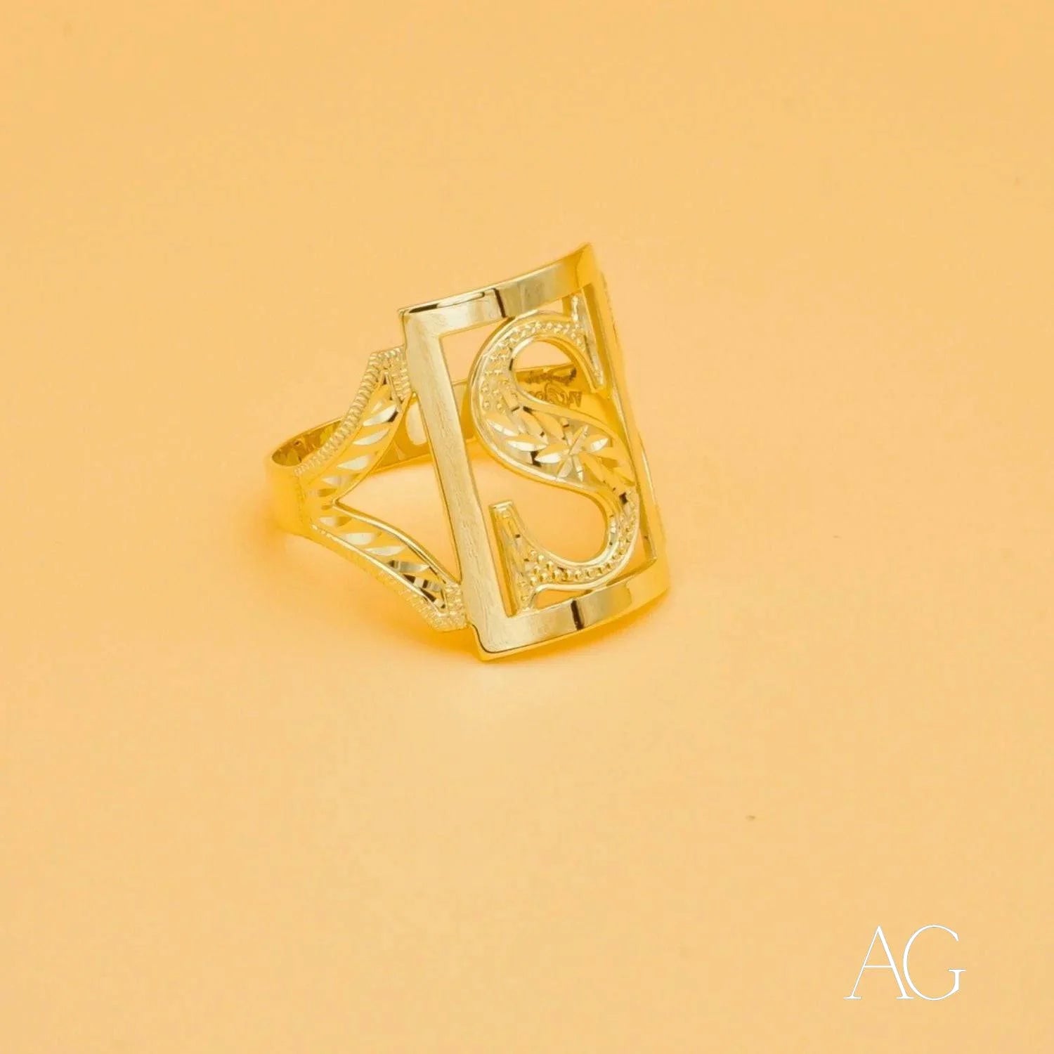 Gold-colored initial letter ring with ornate openwork design and curved elements