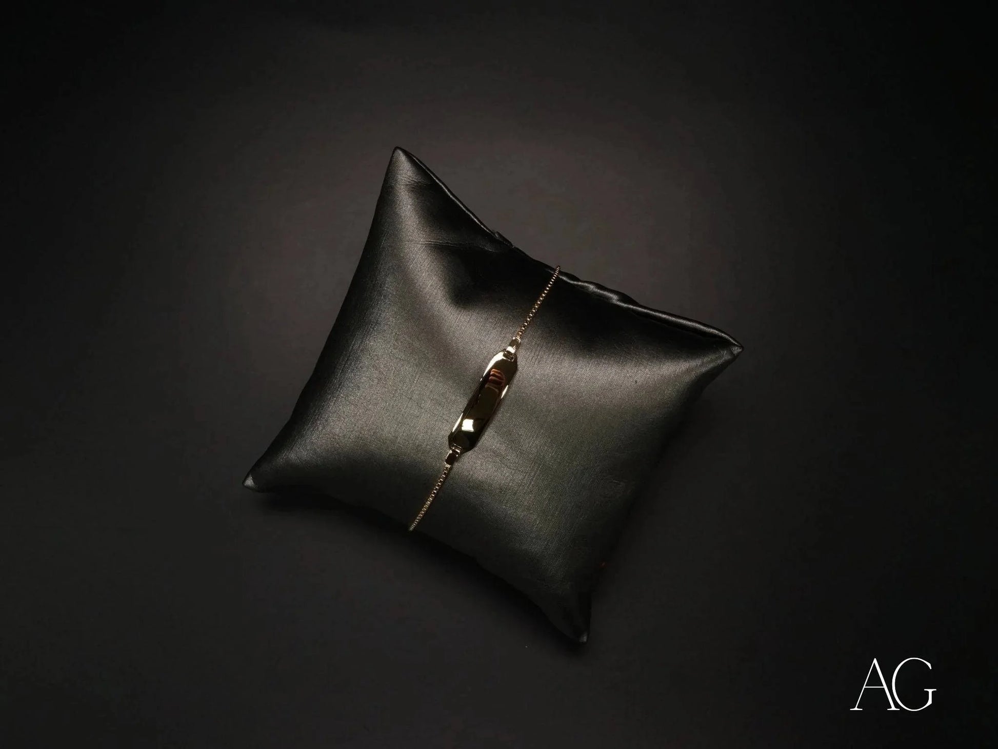 Black leather cushion with a metallic button showcasing an Elegant 18k Gold Kid’s ID Bracelet