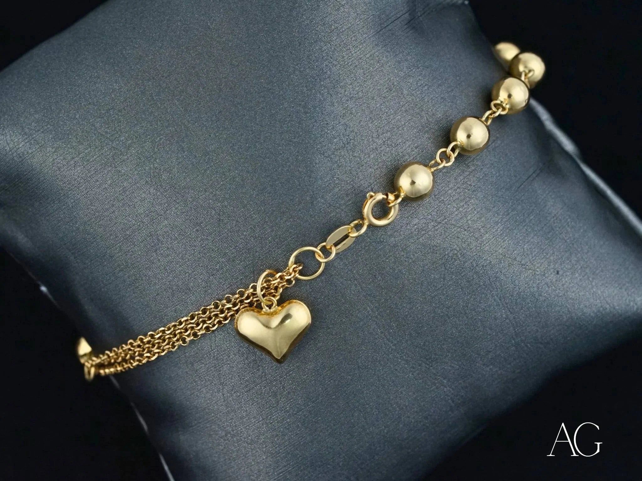 Elegant 18k gold bracelet featuring heart motif and polished gold beads for style