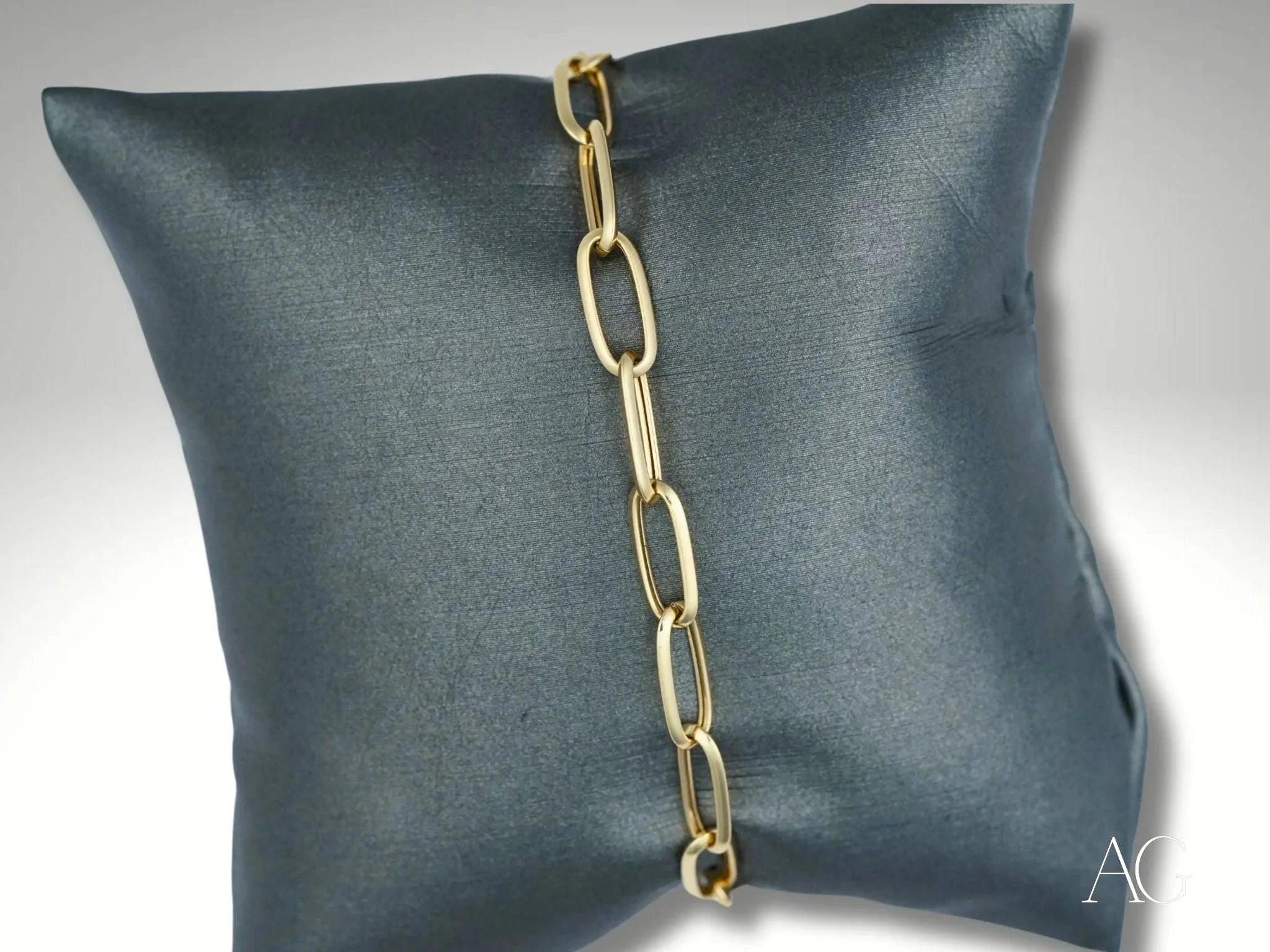 Elegant 18k gold heart-shaped lobster clasp bracelet on a dark gray cushion