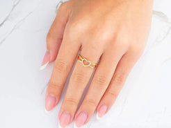 Delicate 18k yellow gold heart ring worn on a finger, symbolizing timeless love