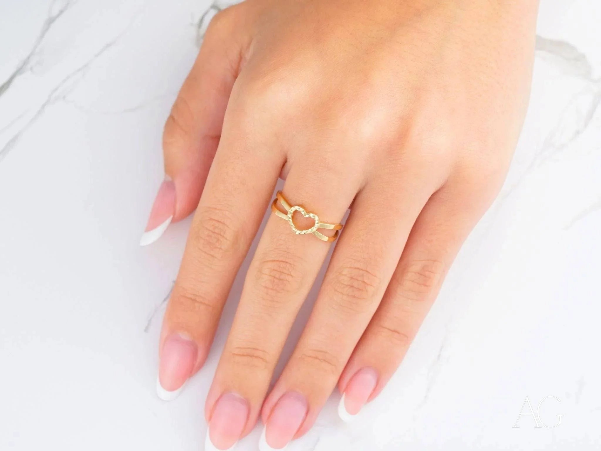 Delicate 18k yellow gold heart ring worn on a finger, symbolizing timeless love