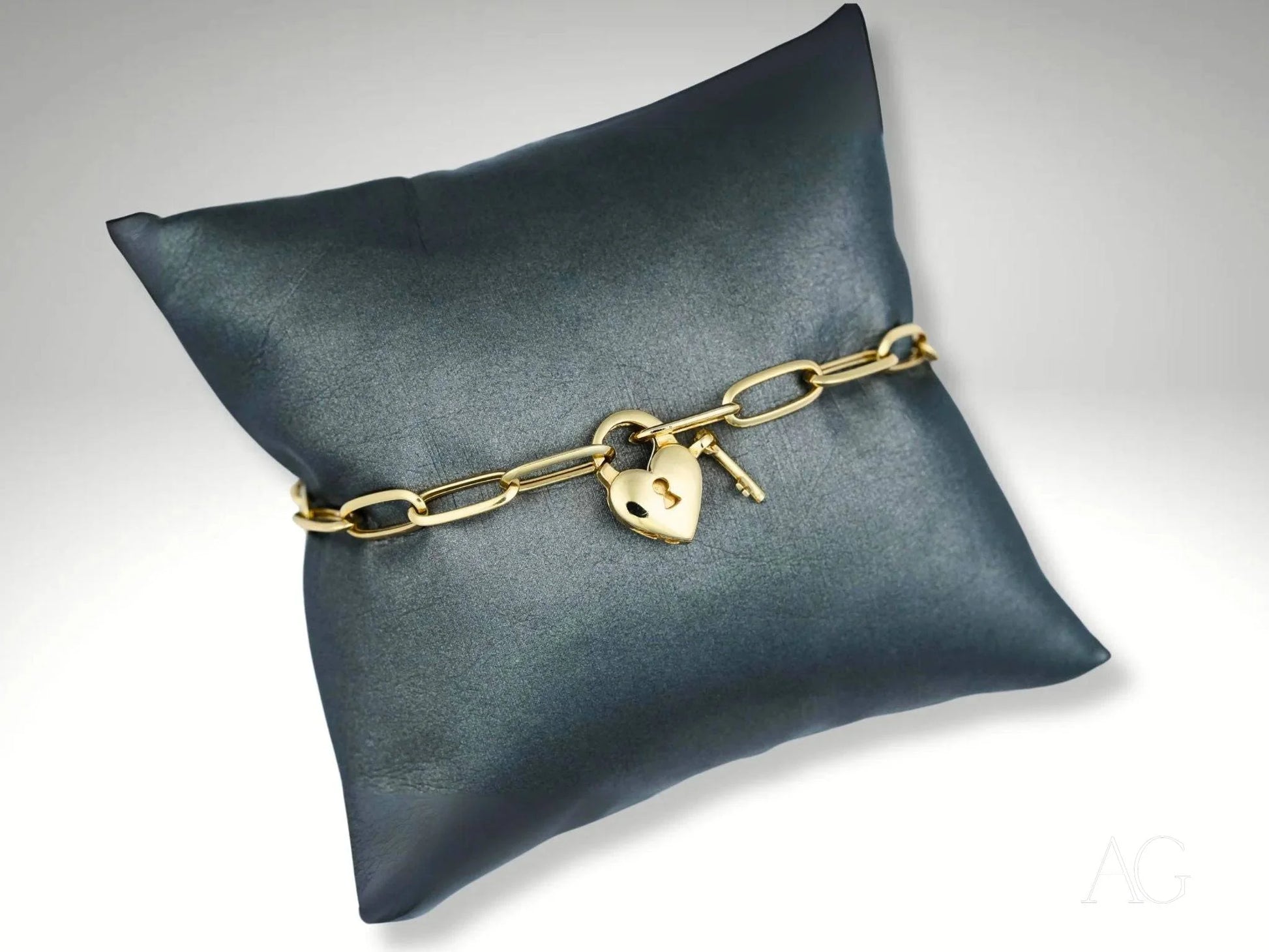 Elegant 18k gold bracelet with heart-shaped lobster clasp on dark cushion