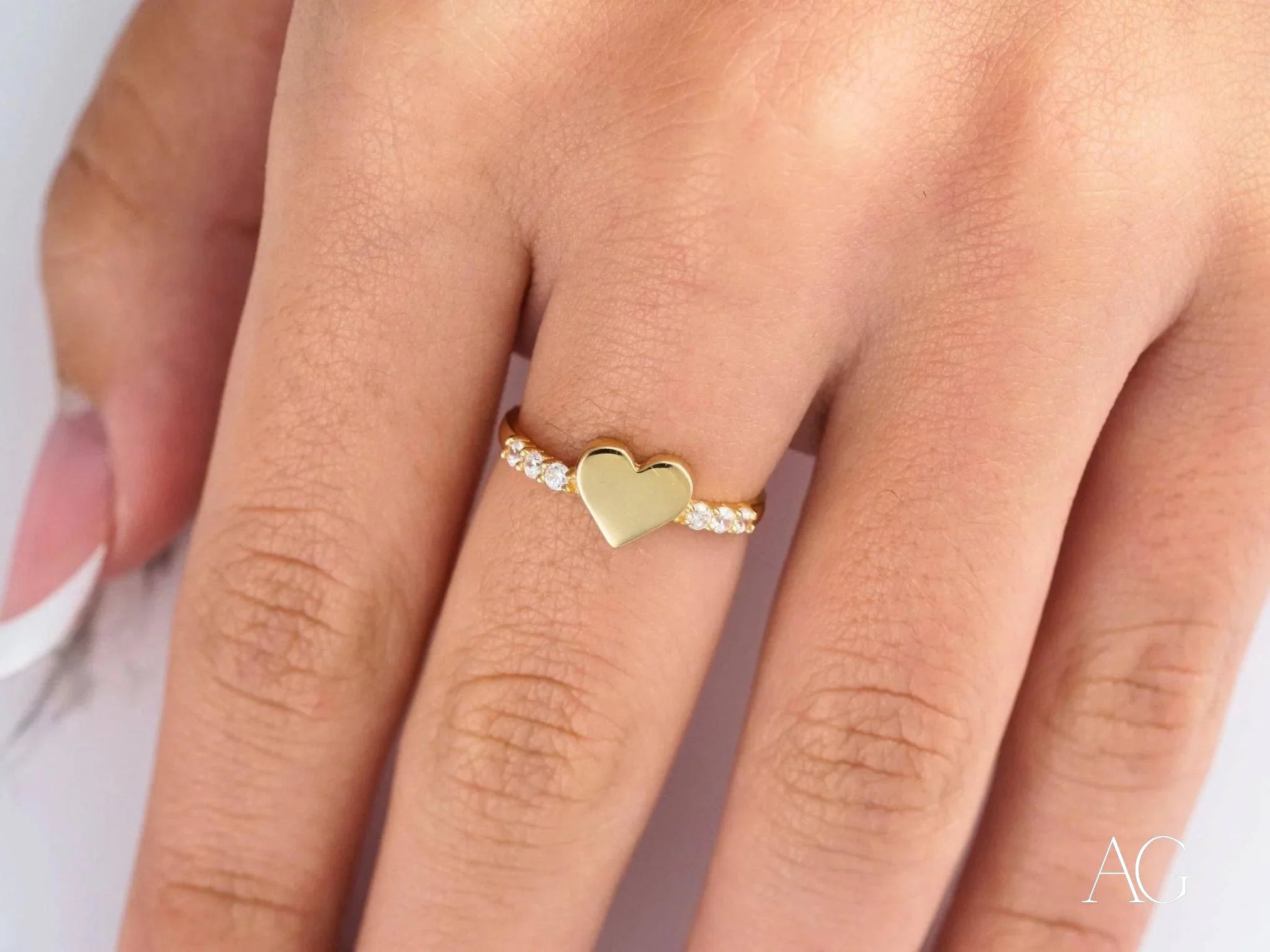 Gold heart-shaped ring in 18k yellow gold elegantly worn on a finger to celebrate love