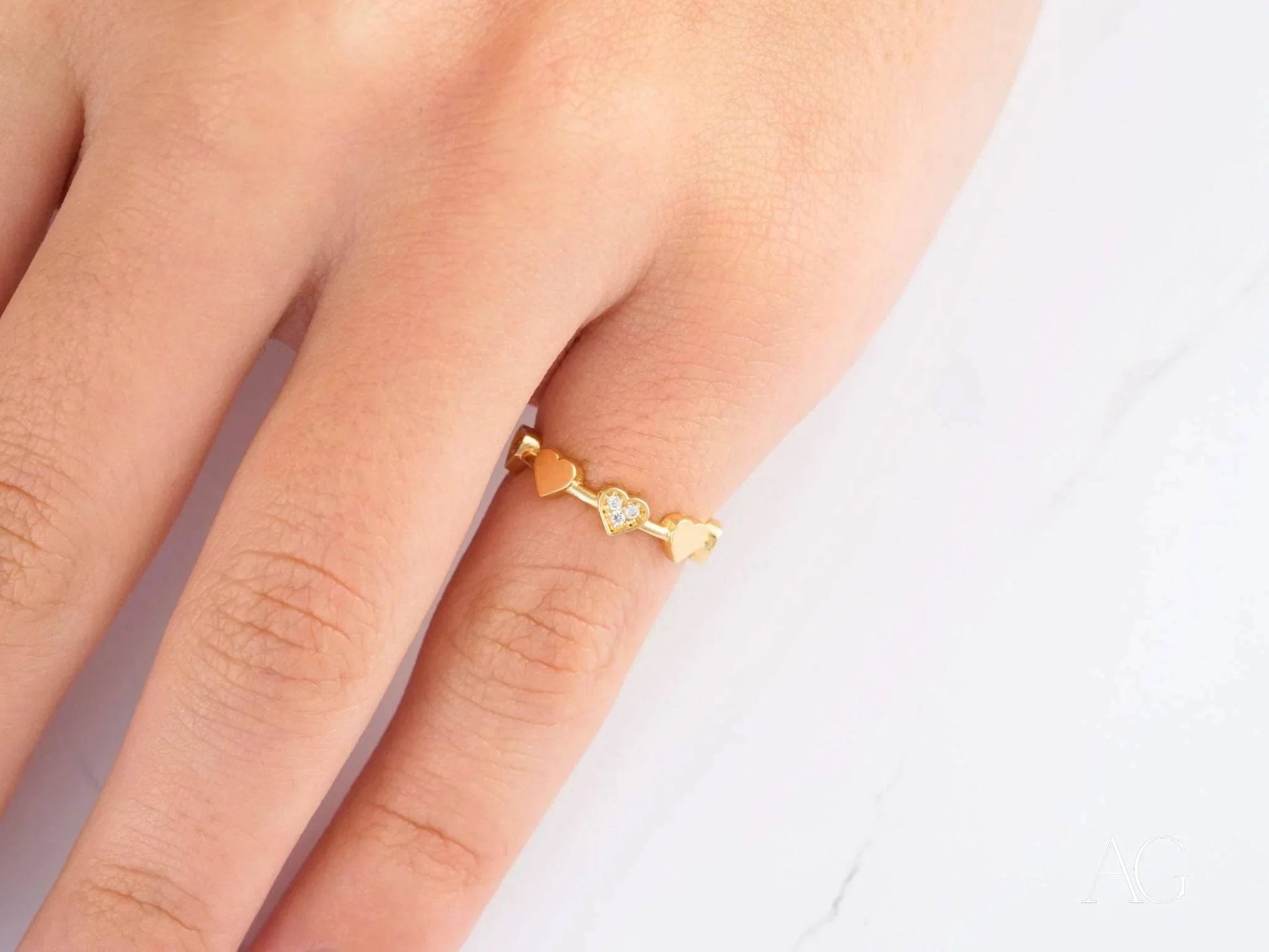 Delicate 18k yellow gold ring with wavy design worn on a finger for elegant style