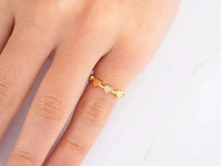 Delicate 18k yellow gold ring with wavy design worn on a finger for elegant style