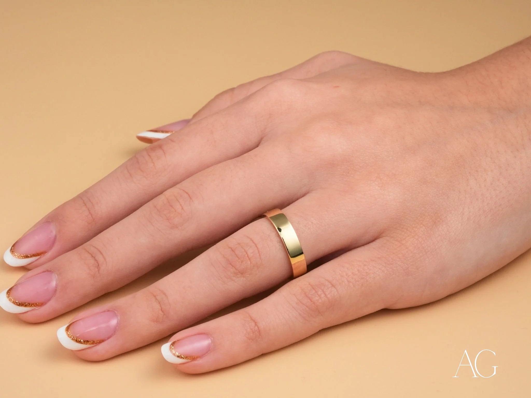 Hand adorned with a minimalistic 18k gold wedding band from the Essence Collection