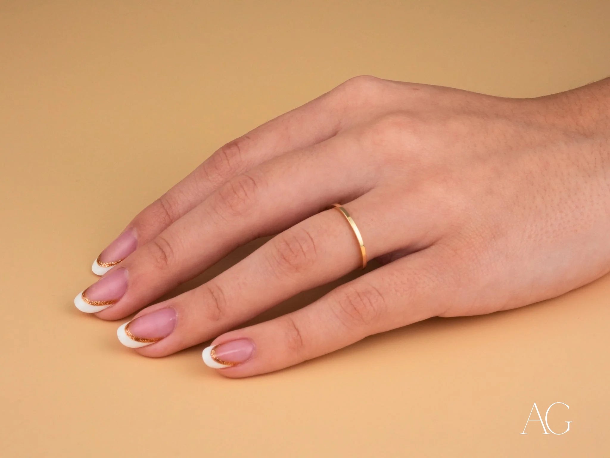 Minimalistic 18k gold ring from Essence Collection on manicured hand