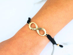 Gold infinity symbol bracelet with forever engraved on a nylon band in 18k gold